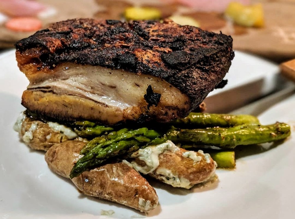 Smoked pork belly with house dry rub served with smashed bleu cheese fingerling potatoes and seasonal vegetables