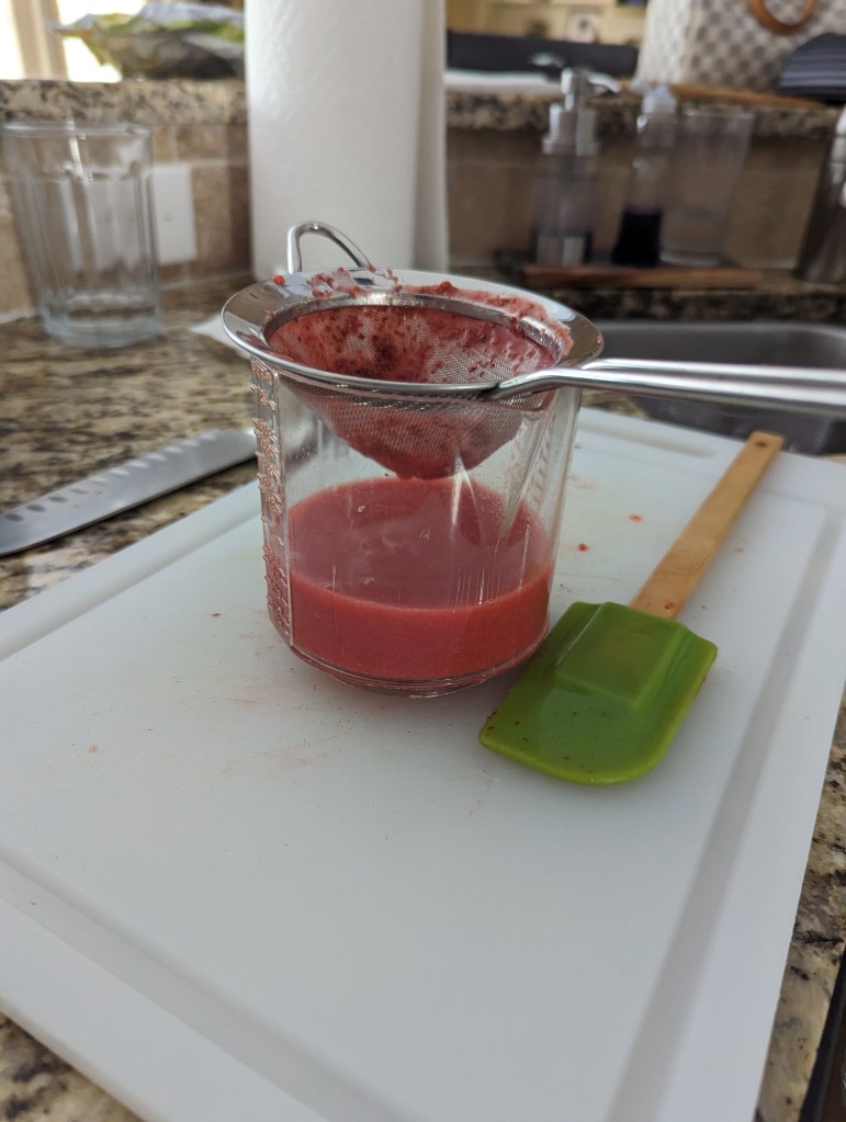 Strawberries being strained to puree.