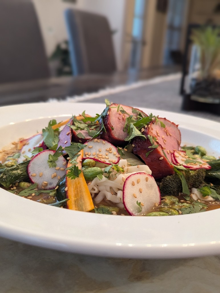 Sous Vide Red Pork (char siu), Blistered Edamame + Steamed Bok Choy, Ramon, Pickled Carrots and Radish, Cilantro, Fried Shallot with Miso Broth