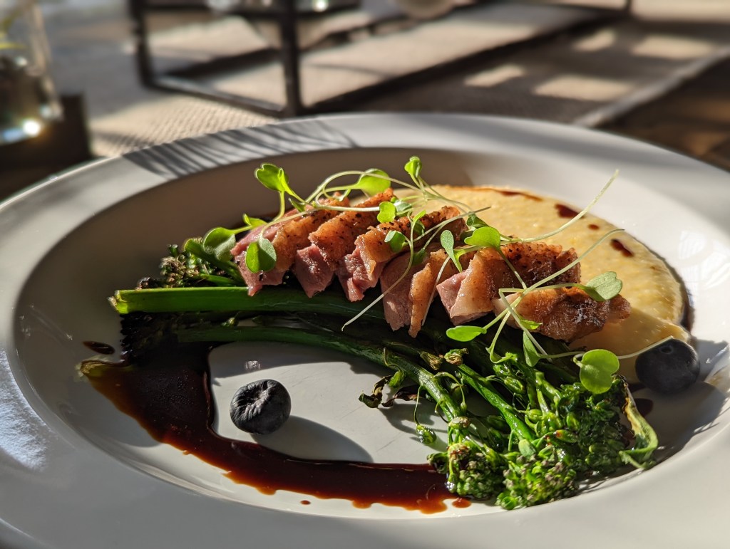 Sous Vide Duck Breast, Gruyère Grits, Duck Fat Charred Broccolini with a Bourbon, Blueberry Balsamic Reduction - Portrait Close