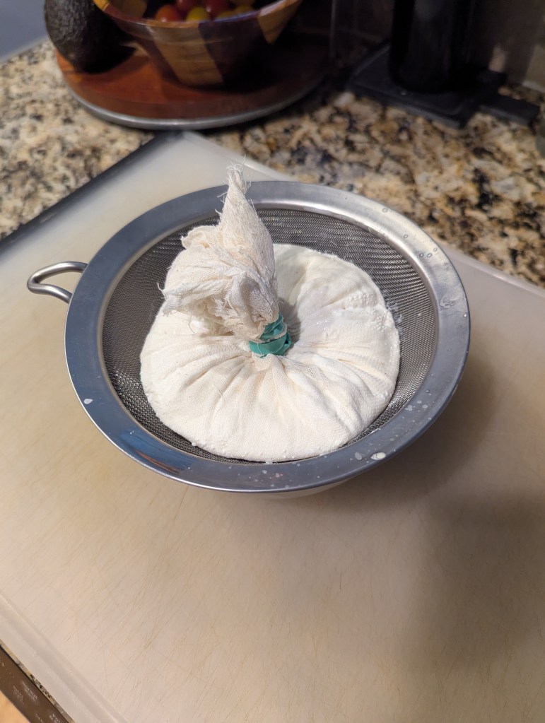 Labneh in the cheesecloth and mesh strainer